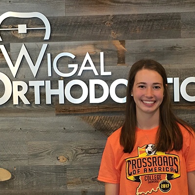 Female patient posing in front of Wigal Orthodontics sign