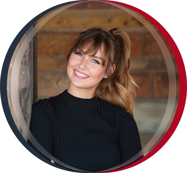 Woman in black coat smiling in front of brick wall