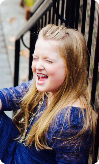 Little girl with braces sitting on stairs outside