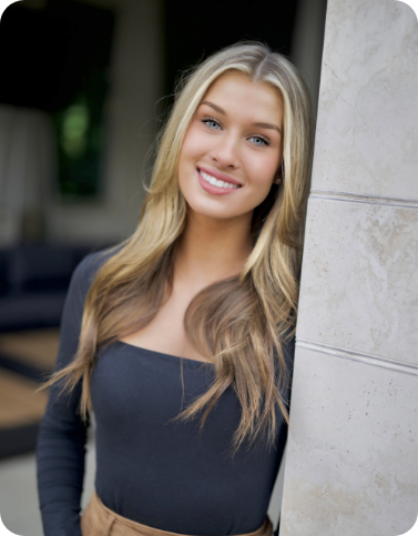 Young woman standing next to wall and smiling