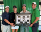 Four people holding a plaque