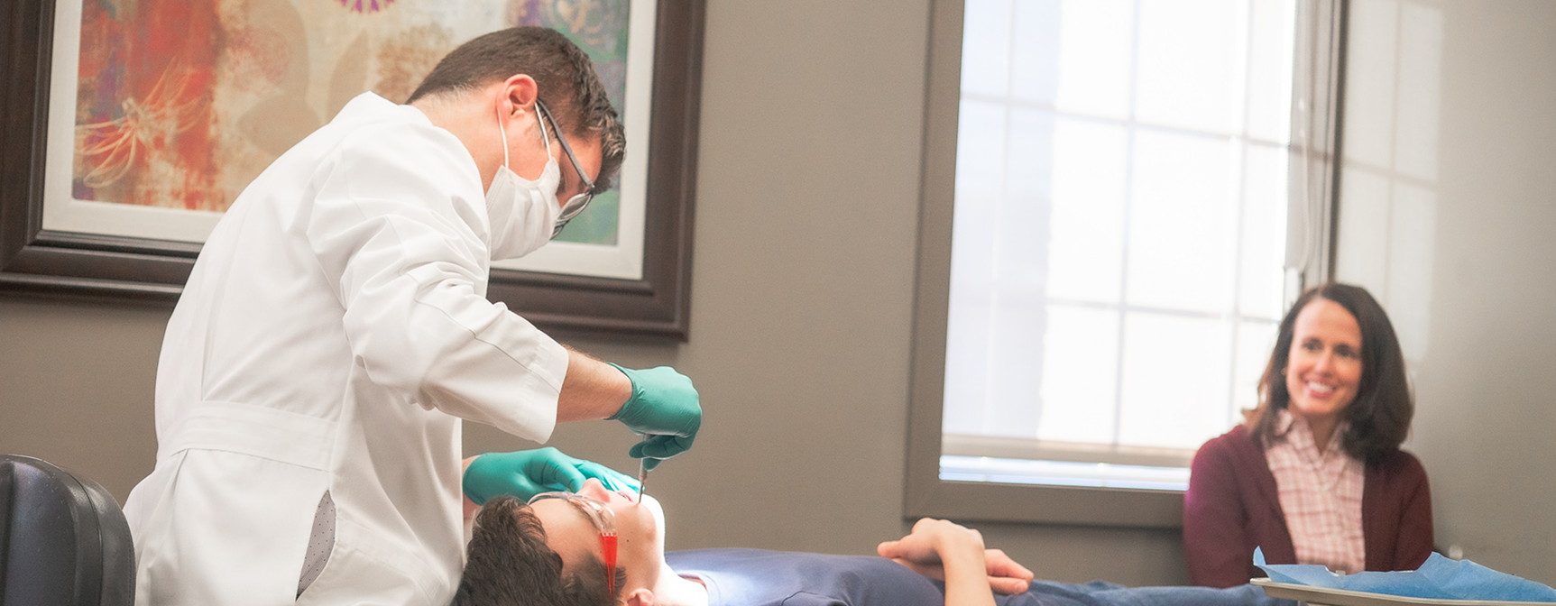 Orthodontist with mask treating patient